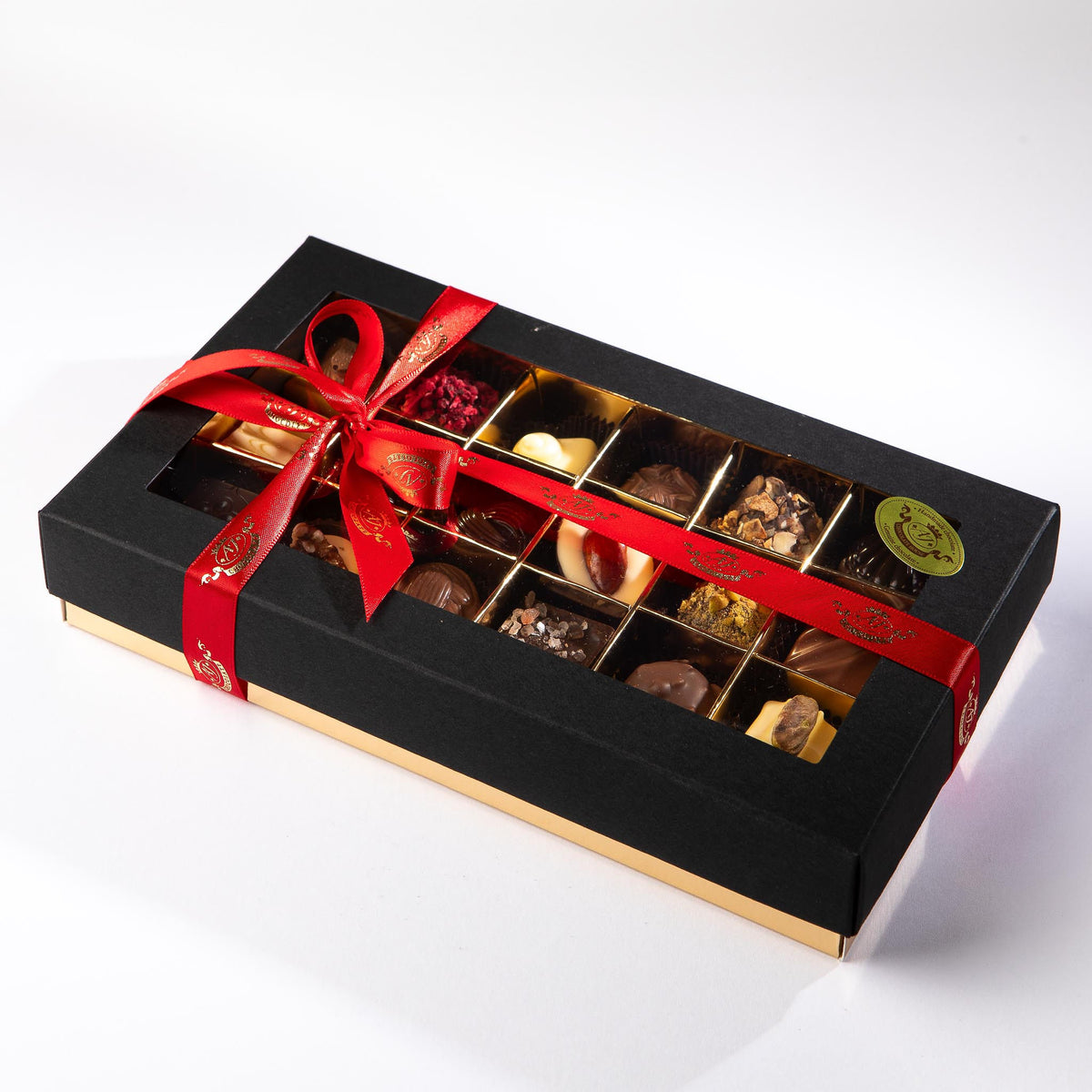 A chocolate box with a clear window displaying various chocolates inside, adorned with a red ribbon.